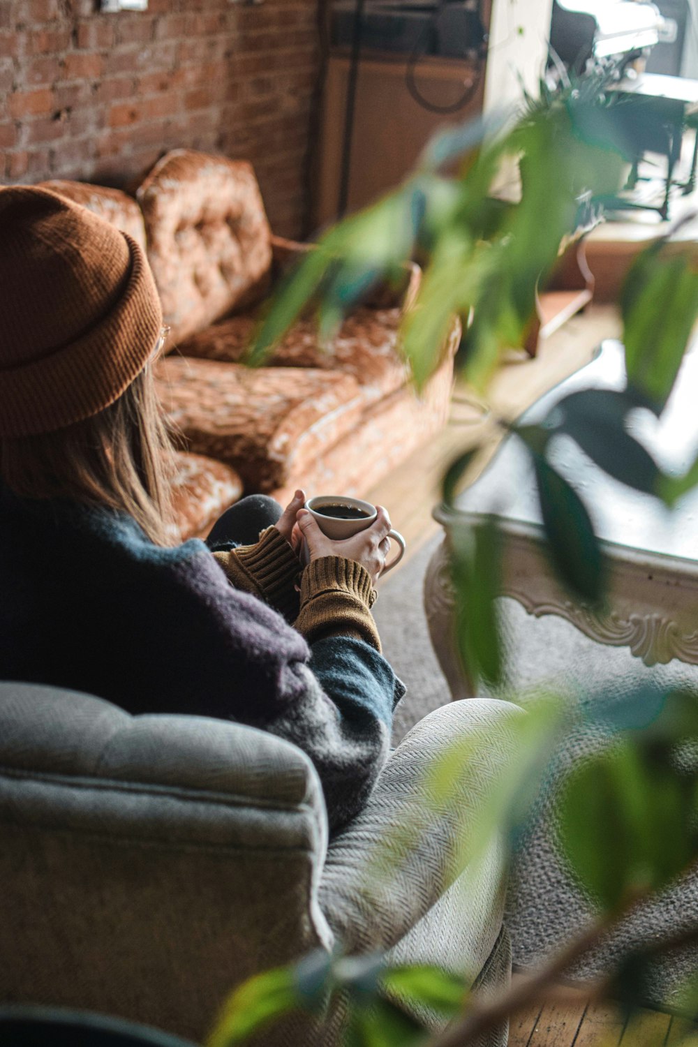 a woman sitting on a couch holding a cup of coffee