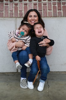 woman in black long sleeve shirt carrying girl in pink jacket