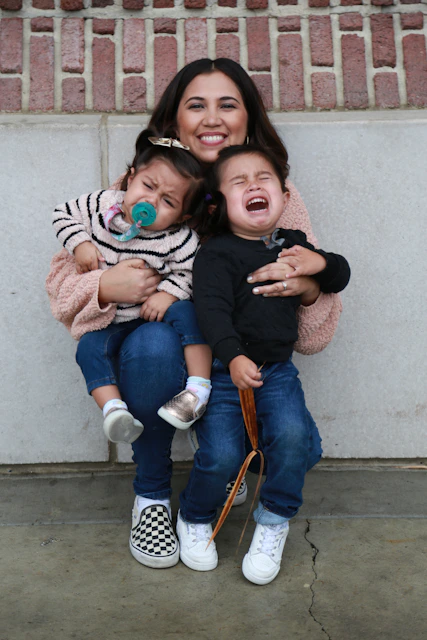 woman in black long sleeve shirt carrying girl in pink jacket