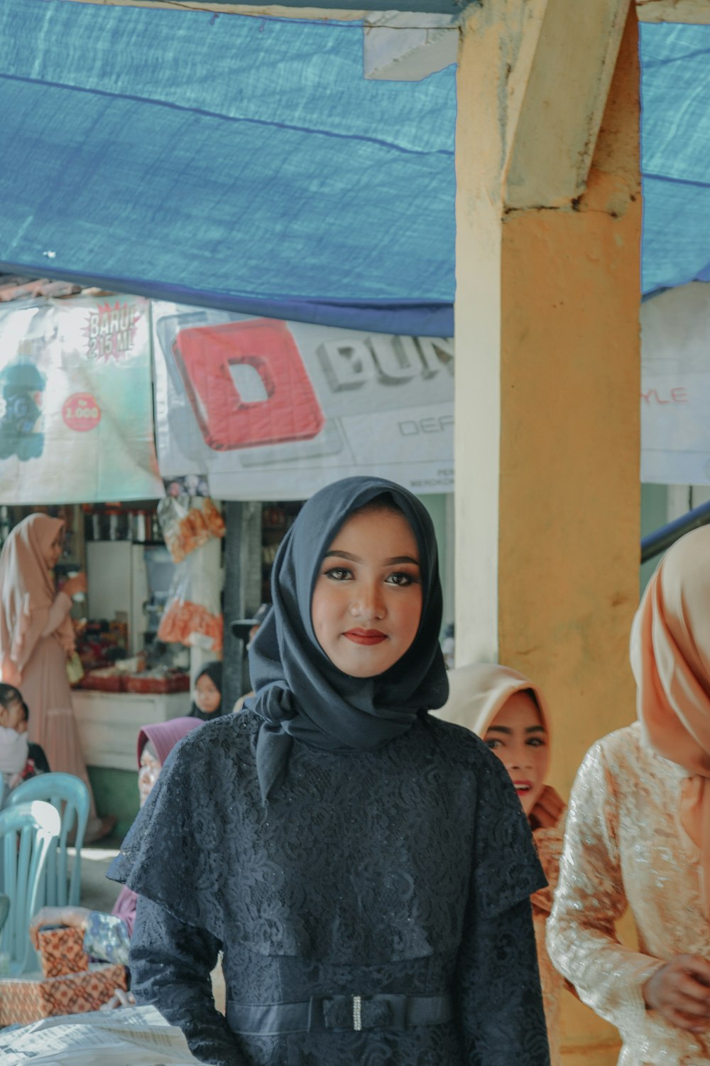 woman in black hijab standing near people sitting on chair