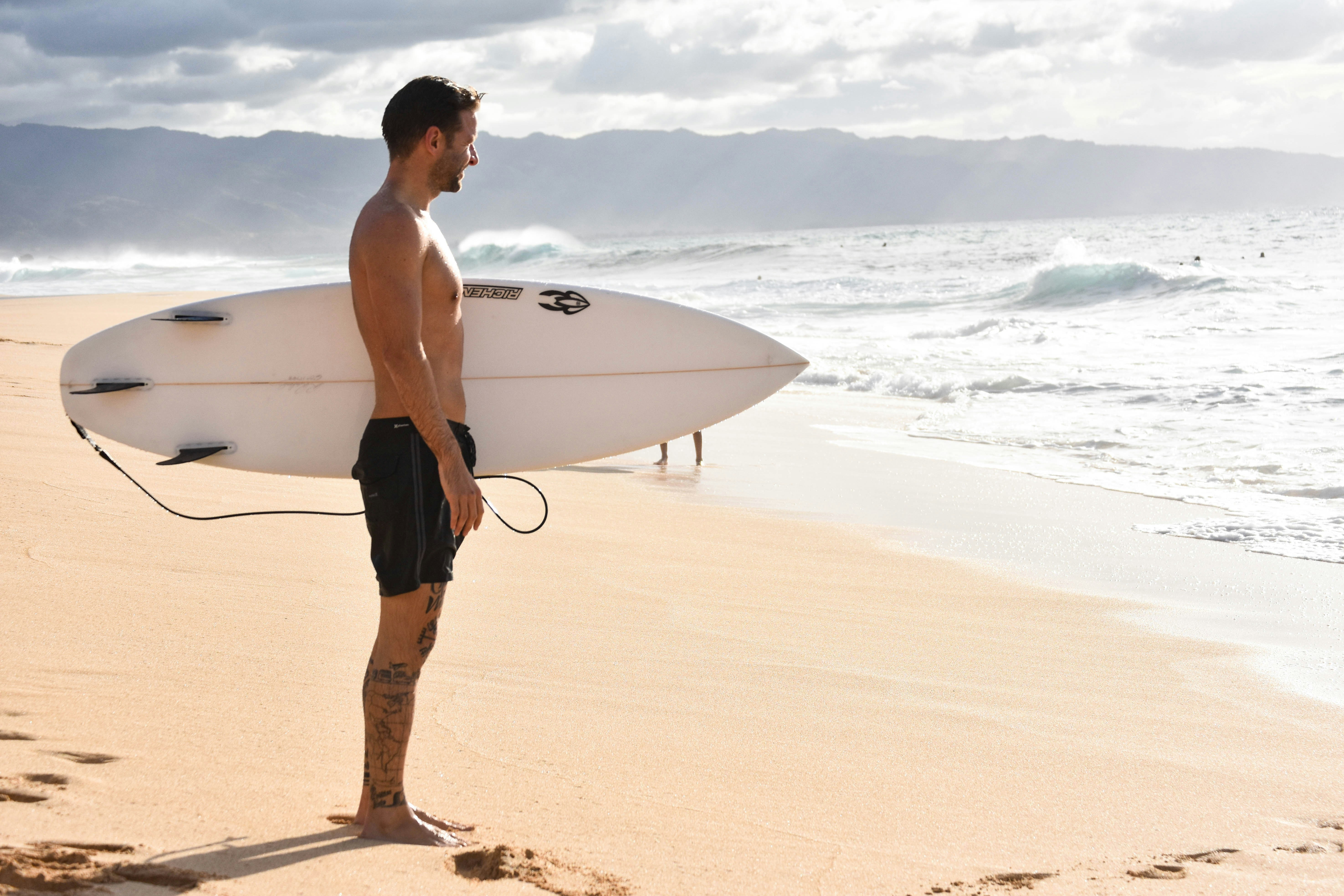 homme en short noir debout sur la plage pendant la journée