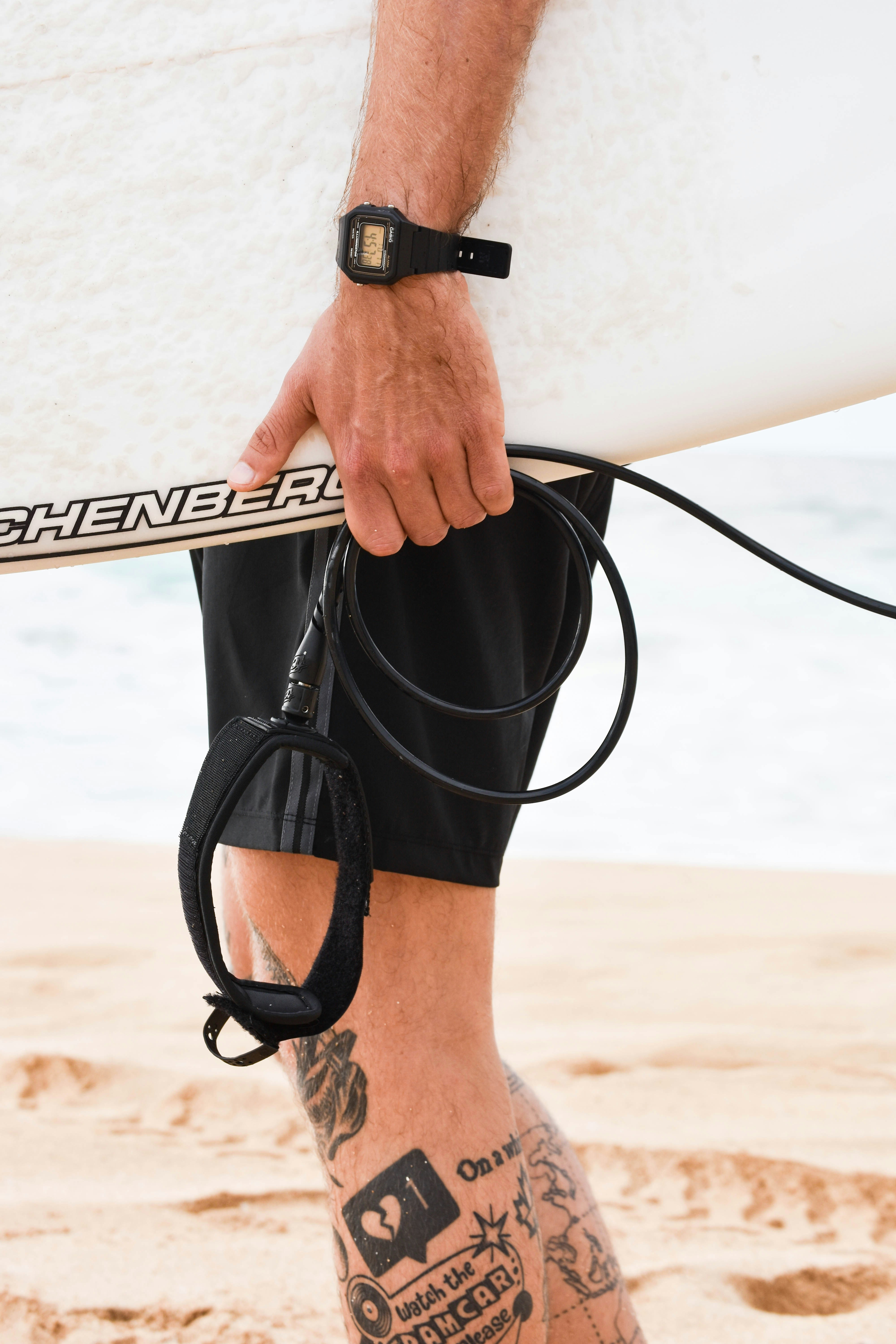 personne tenant une planche de surf blanche et noire