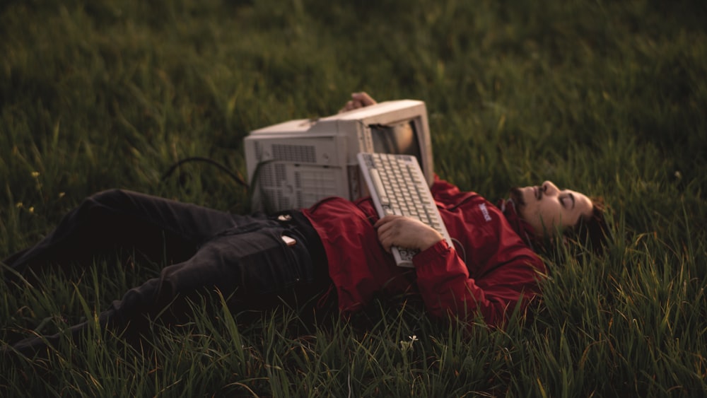 uomo in felpa con cappuccio rossa sdraiato sul campo di erba verde