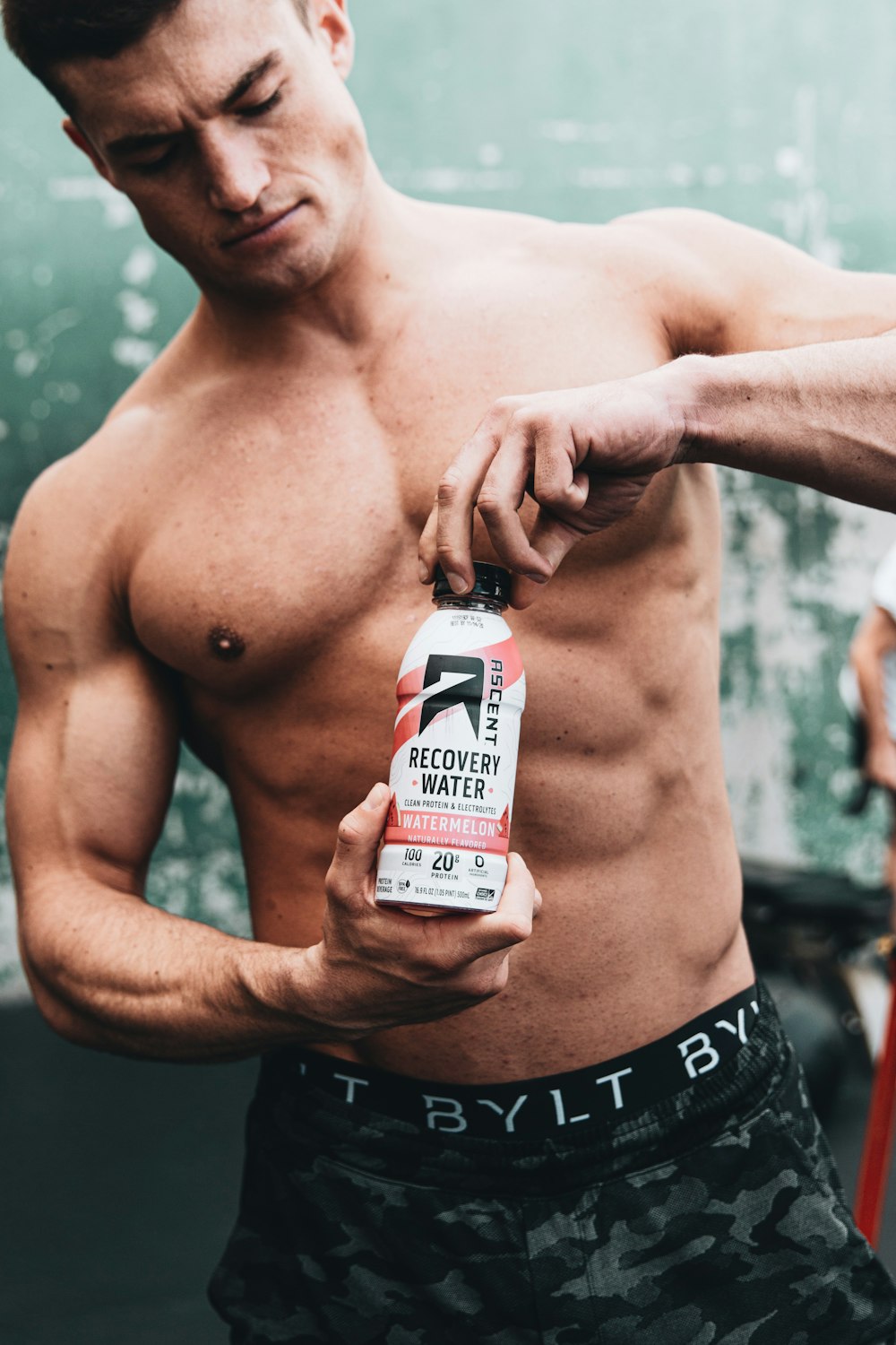 topless man holding white and black bottle