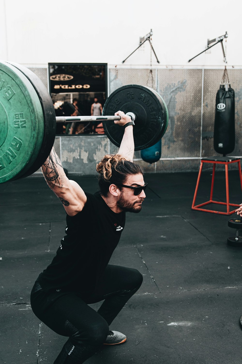 woman in black tank top holding green barbell