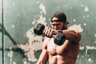 topless man holding black dumbbell