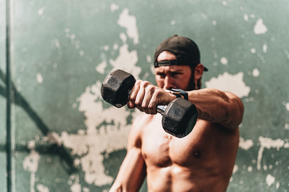 topless man holding black dumbbell