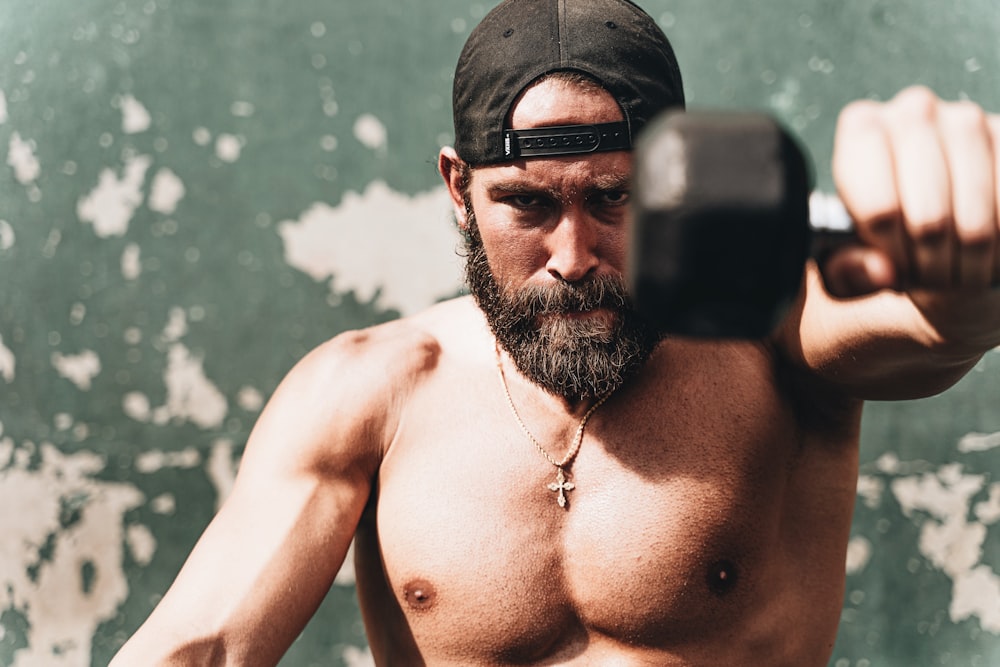 topless man wearing black sunglasses and black cap