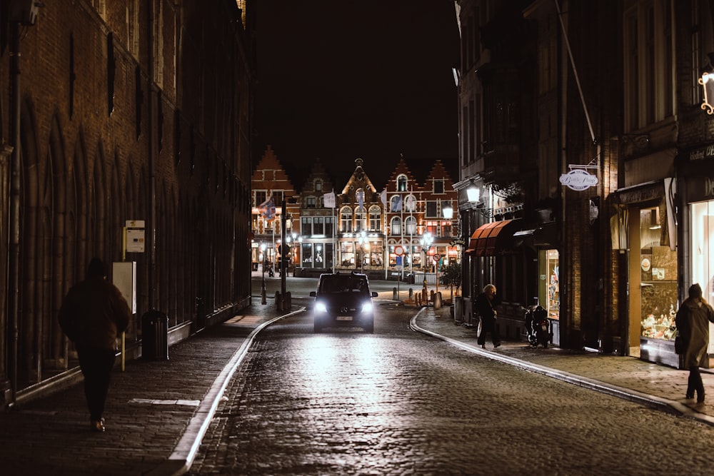 black car on road between buildings during night time