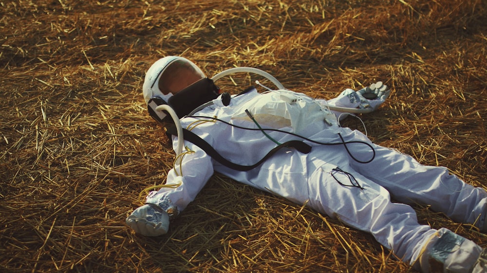 man in white and black suit lying on brown grass
