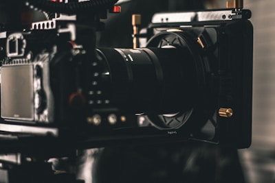 A professional video camera with intricate components and a large lens is mounted on a stabilizing rig, suggesting it is ready for high-quality filming. The image captures various details of the camera, such as its control buttons and precision-focused features.