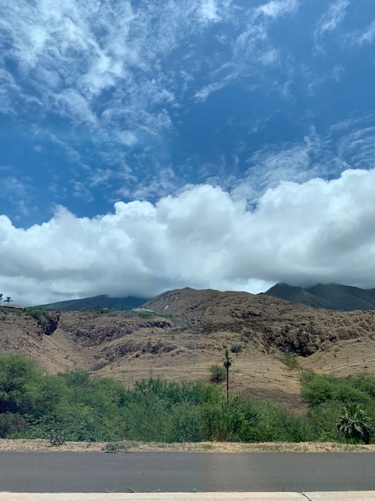 green grass field on brown mountain under white clouds and blue sky during daytime in Maui United States