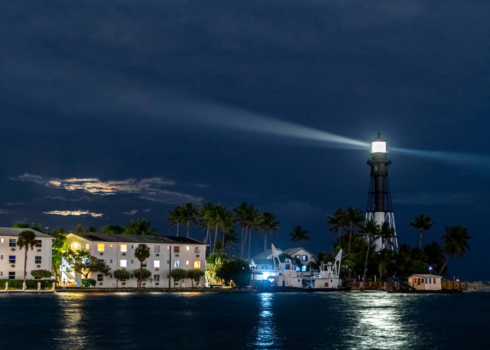 edificio in cemento bianco e marrone vicino allo specchio d'acqua durante la notte