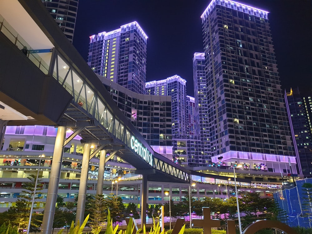 people walking on sidewalk near high rise buildings during nighttime