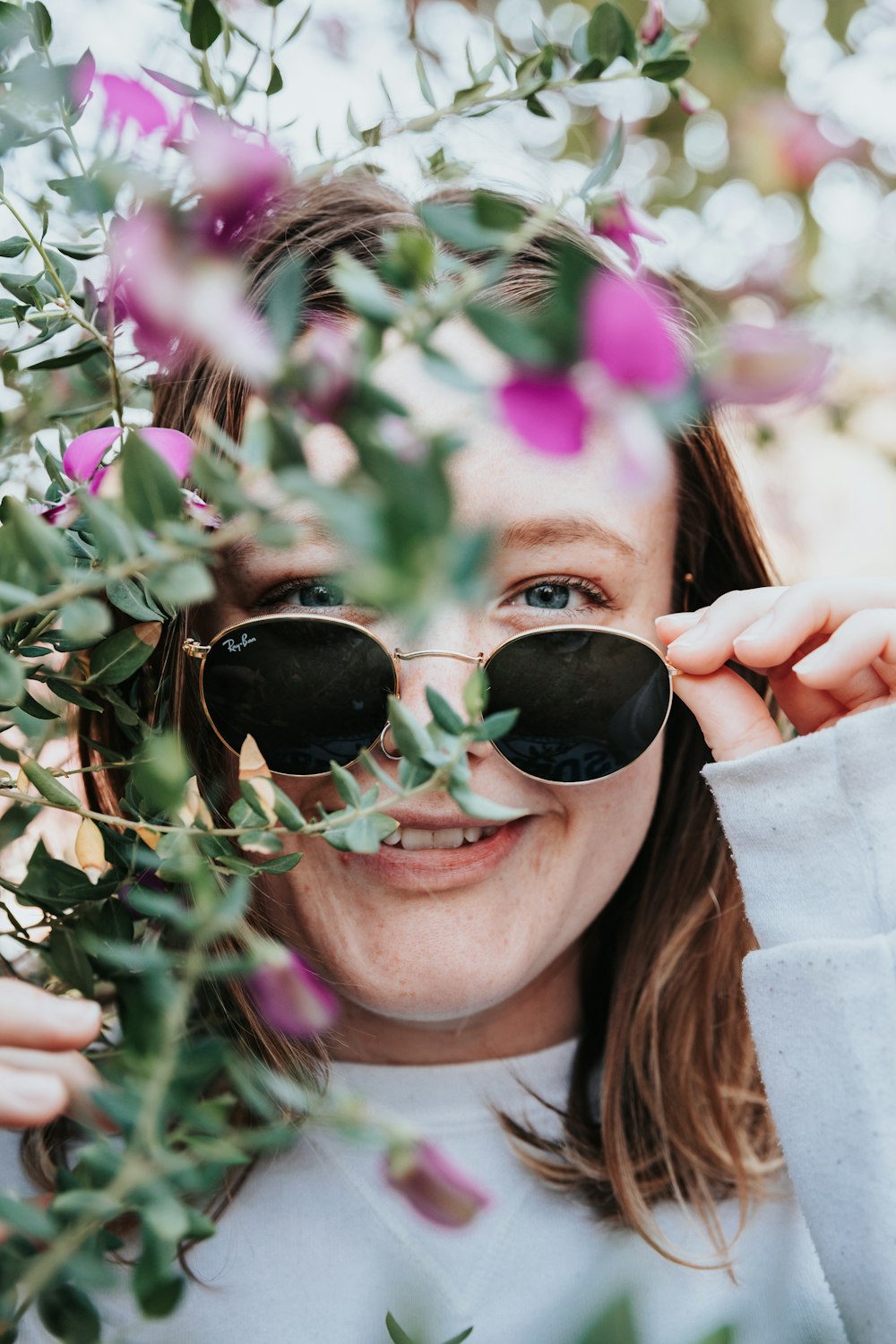 woman in black sunglasses holding green leaves