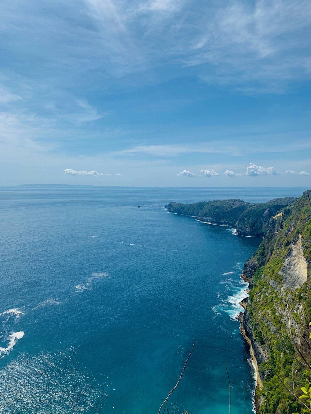 green and brown mountain beside blue sea under blue sky during daytime