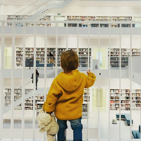 A hand reaching for a book on a library shelf, symbolizing reading intervention and literacy programs at public elementary schools