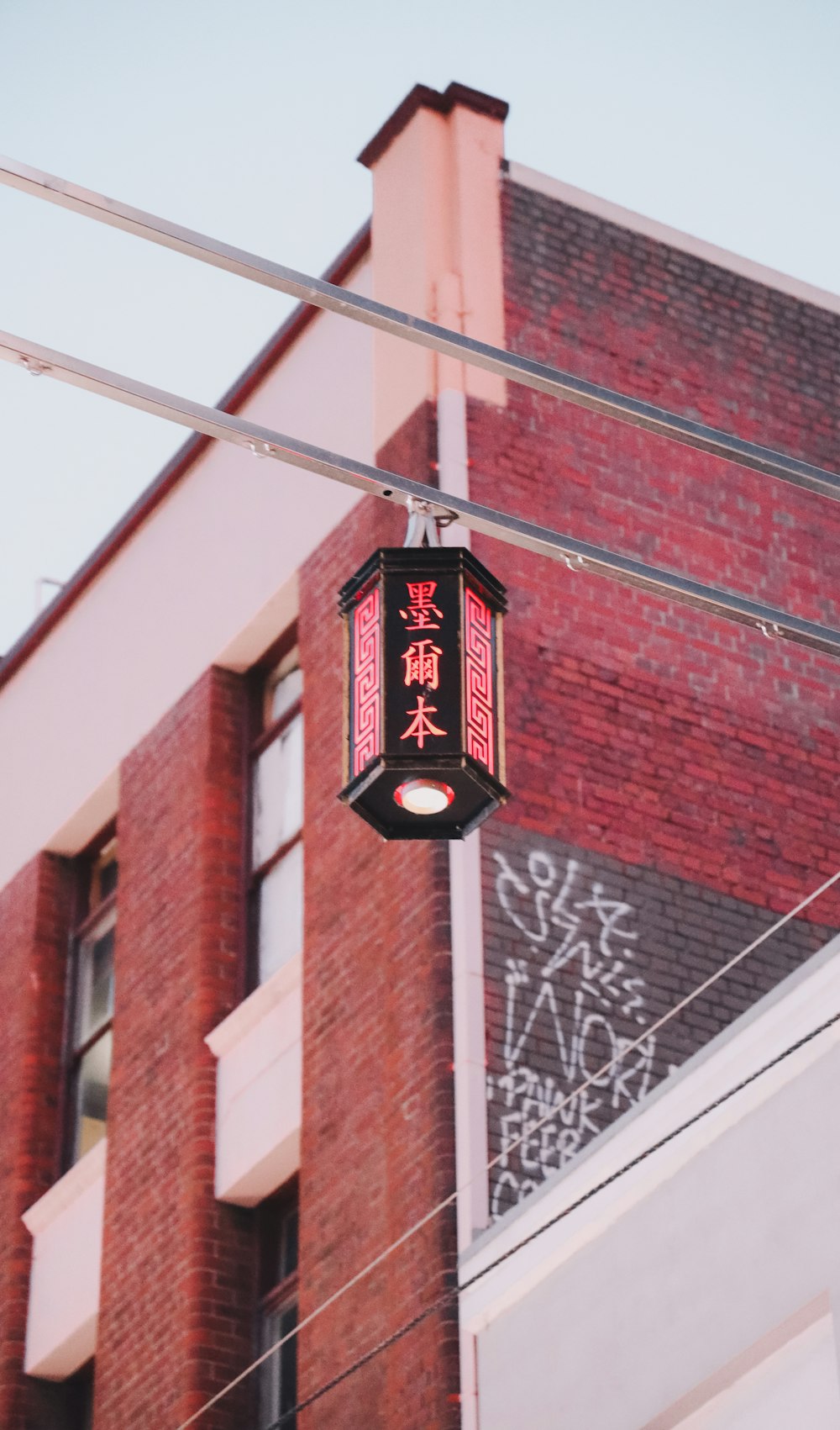 a red light hanging from a wire next to a building