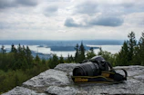 Perle Path camera bag resting on a rocky ledge overlooking a vast mountain landscape.
