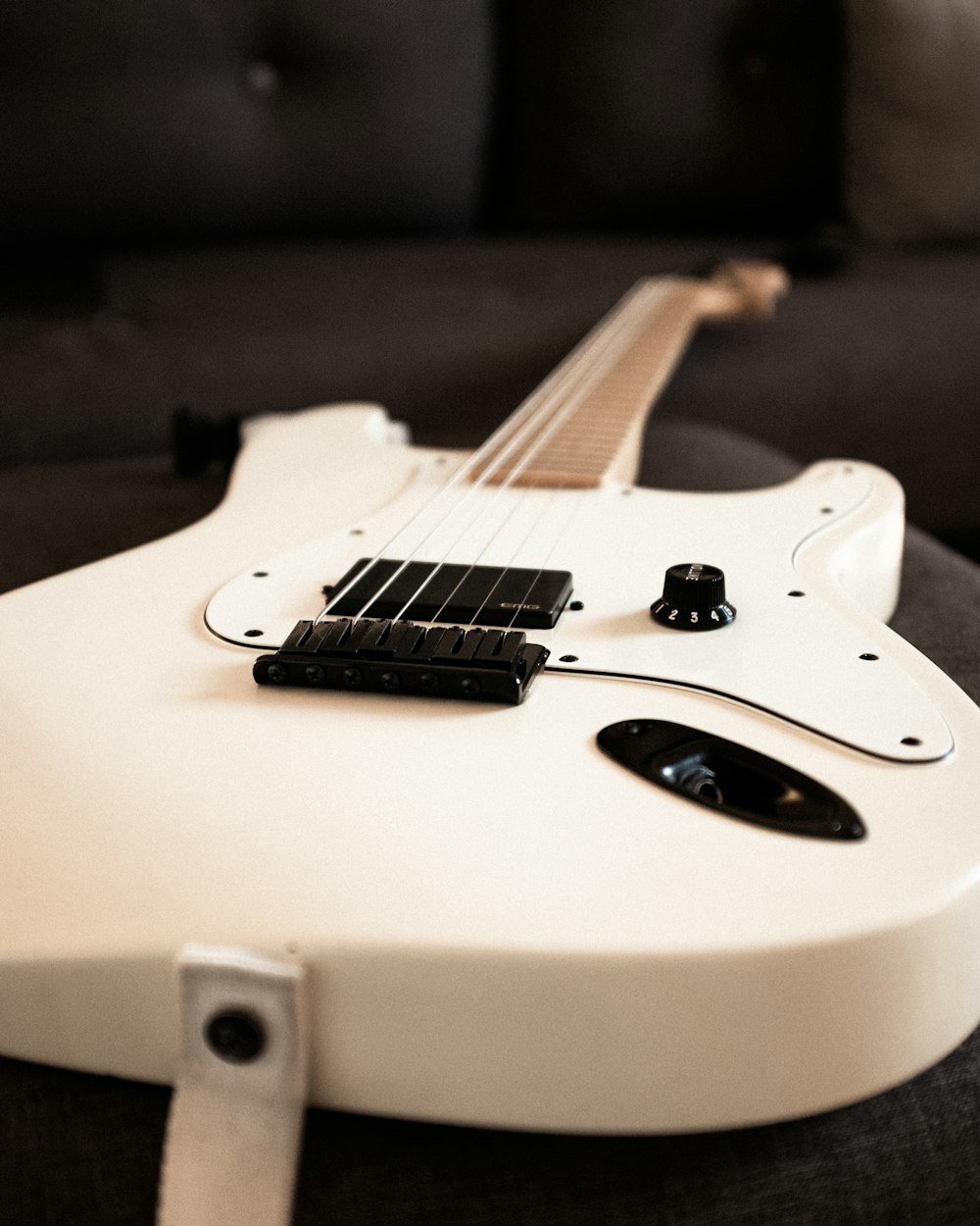 a white electric guitar sitting on top of a couch