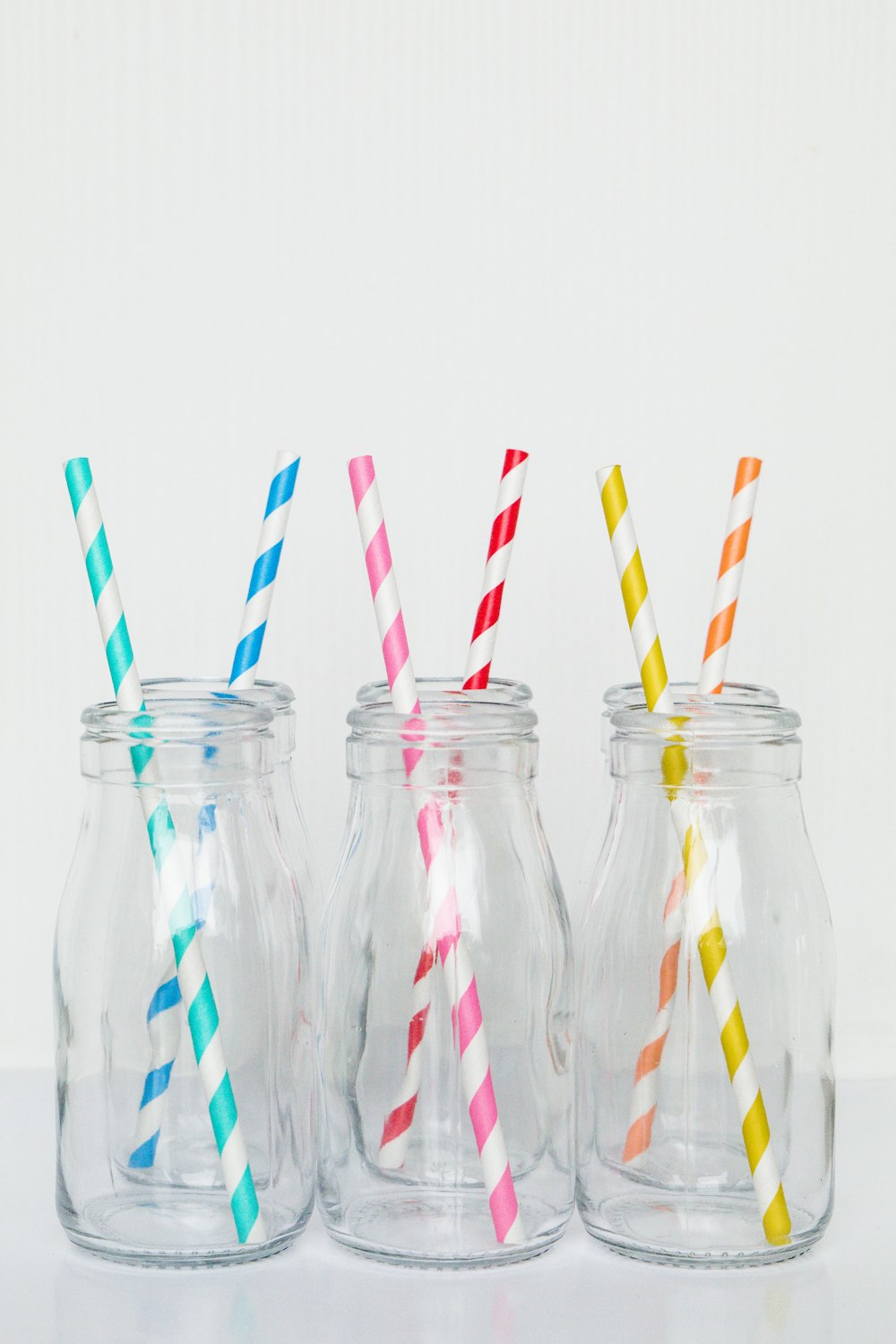 Botellas de vidrio transparente con pajita de rayas rojas, blancas y azules