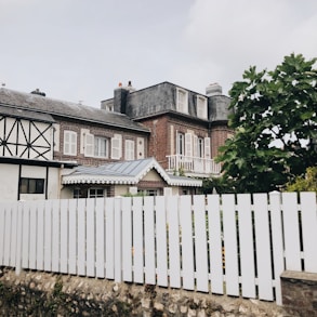 white wooden fence near white and brown house