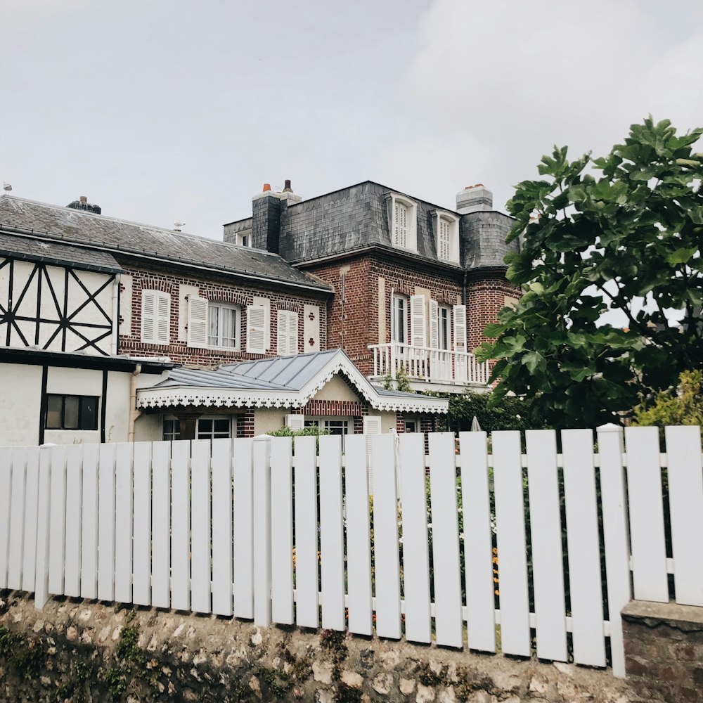 white wooden fence near white and brown house