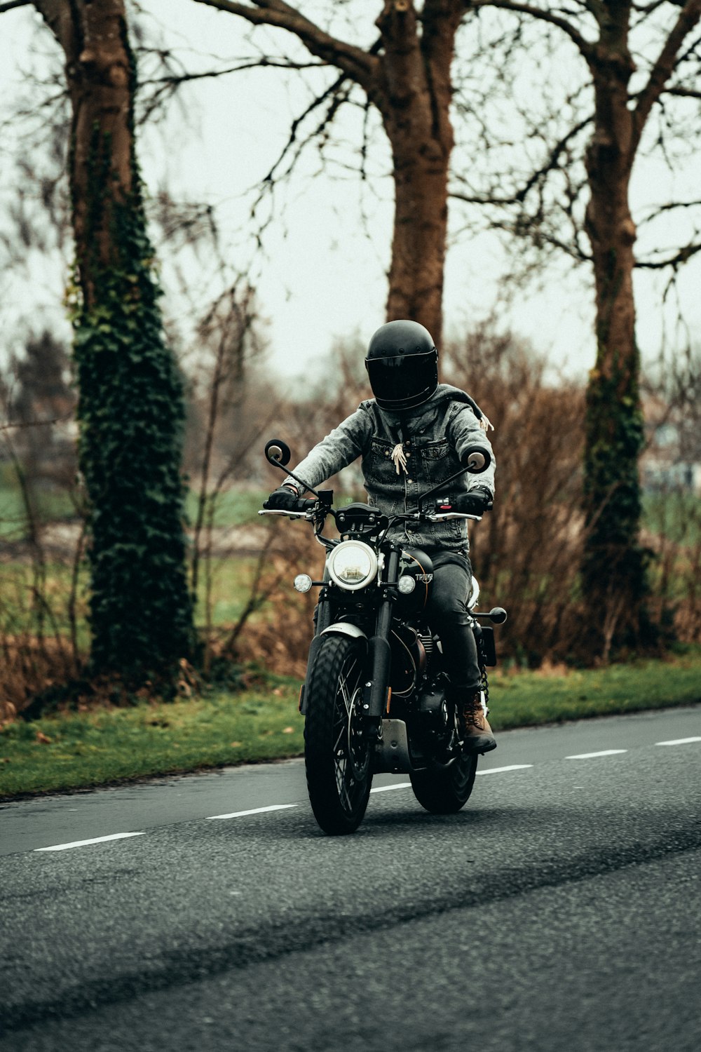 낮 동안 도로에서 오토바이를 타는 검은 재킷을 입은 남자