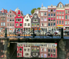 Bicycles parked on a bridge over a canal in Amsterdam with historic buildings