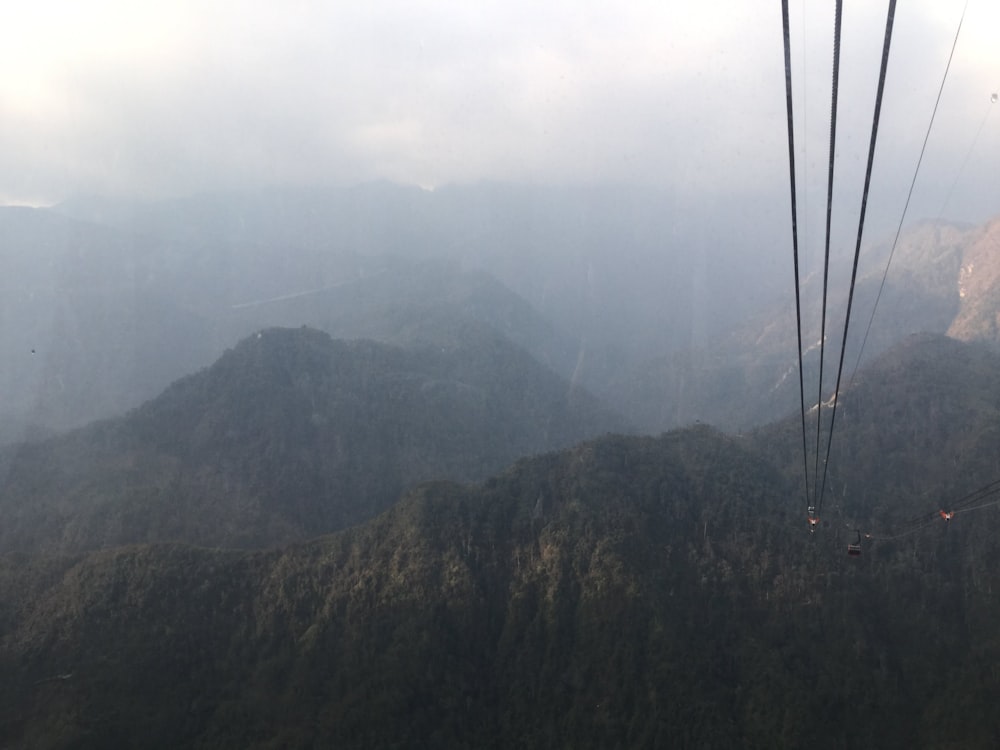 black cable wire over green mountains during daytime