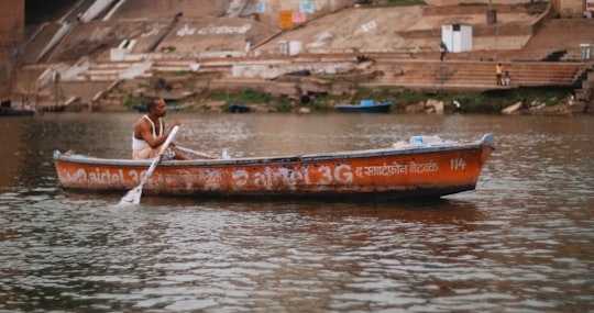 woman in red and white bikini riding on red boat during daytime in Varanasi India