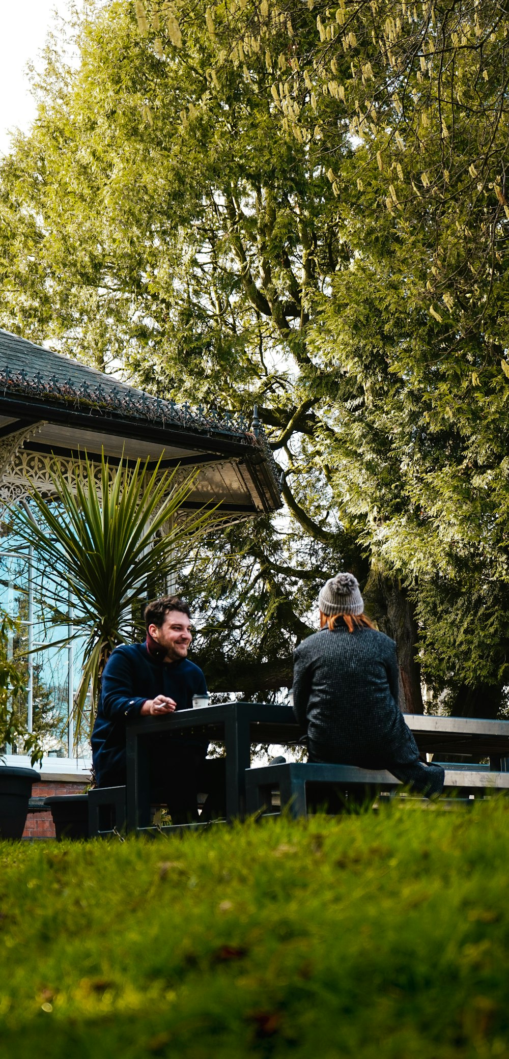 man in blue long sleeve shirt sitting on brown wooden bench