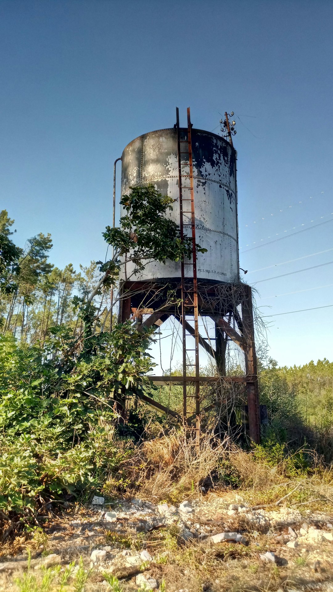 white water tank on brown grass field under blue sky during daytime