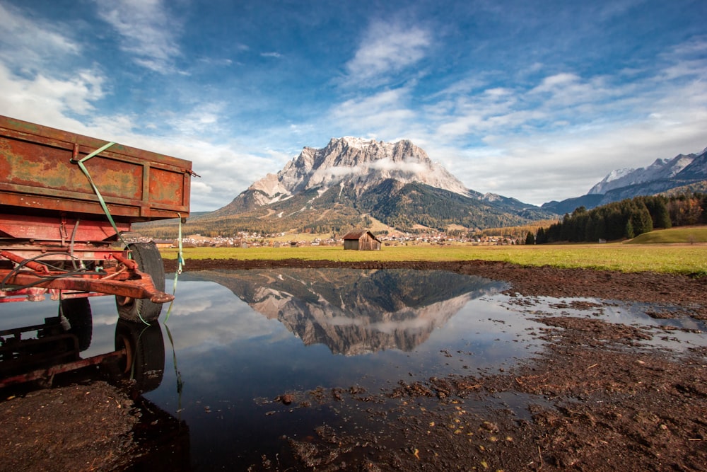 brown wooden house near lake and mountain under blue sky during daytime