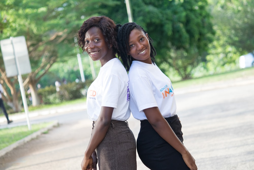 2 women in white polo shirt standing on road during daytime