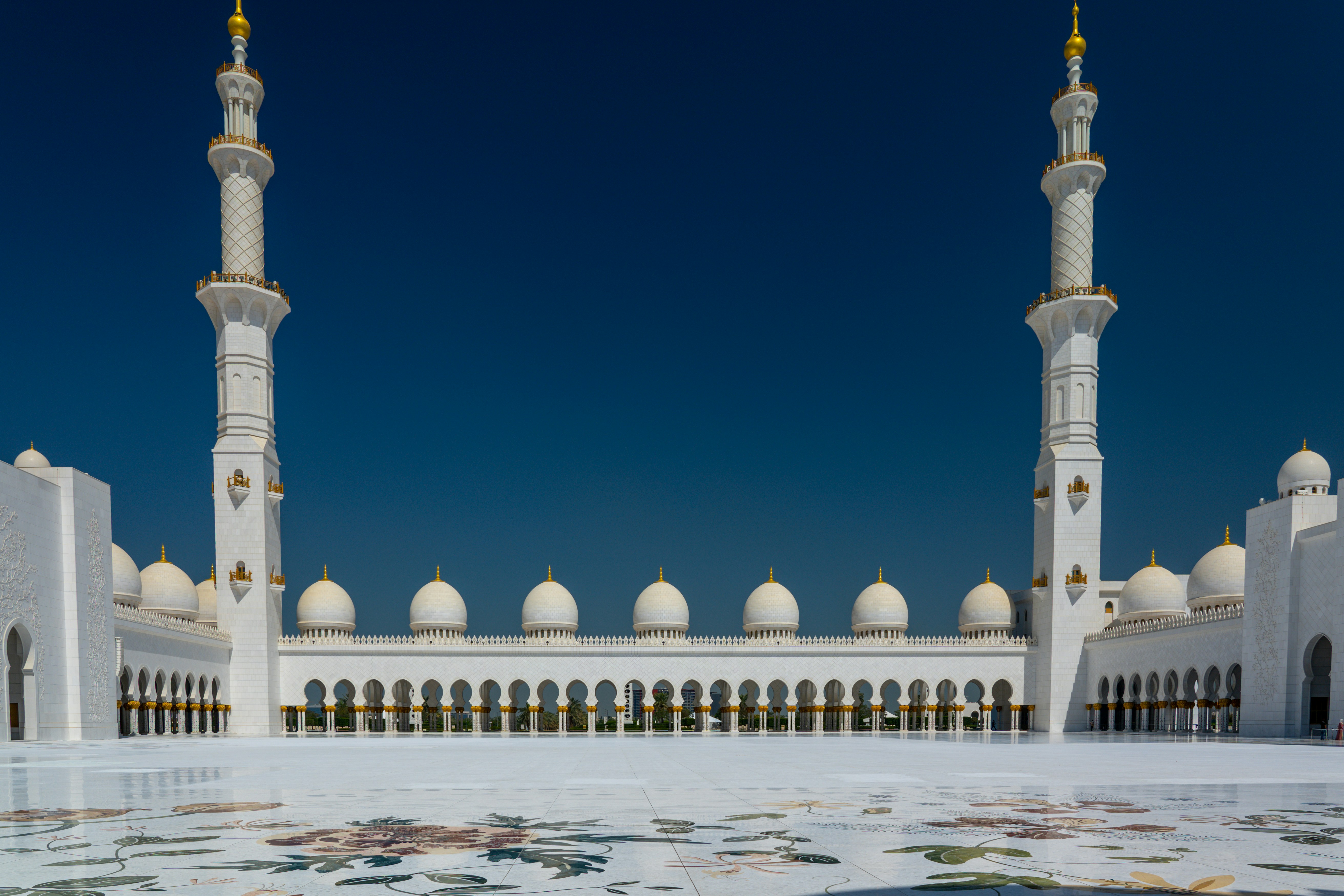 white and gold mosque under blue sky during daytime, Two of the four minarets of the Sheik Zayed Grand Mosque, Abu Dhabi.  Most of the outer court is made from marble imported from Italy and is inlaid with flowers.