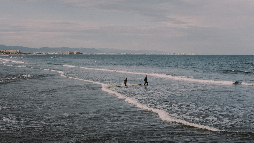 2 people surfing on sea waves during daytime