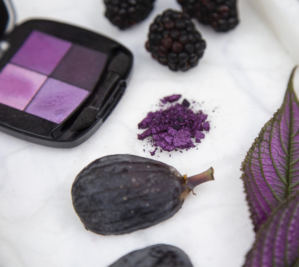 black and purple round fruit beside purple and black eyeshadow palette