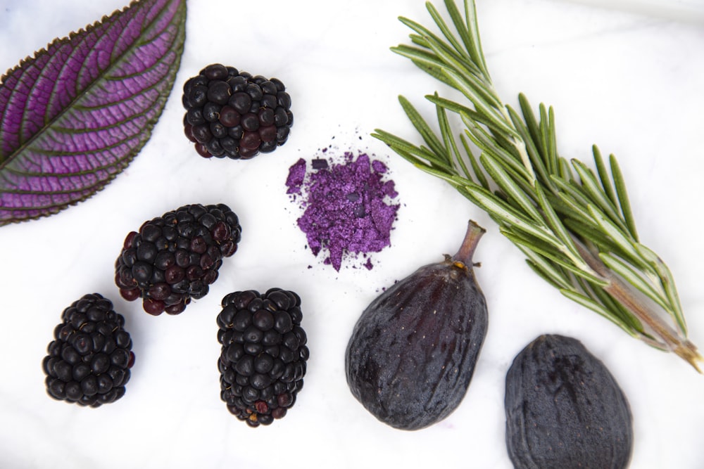 purple round fruit on white surface