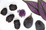 purple round fruit on white surface