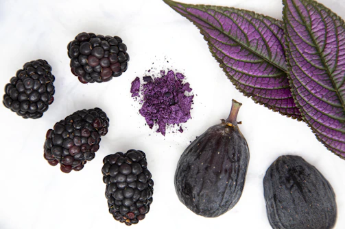 purple round fruit on white surface