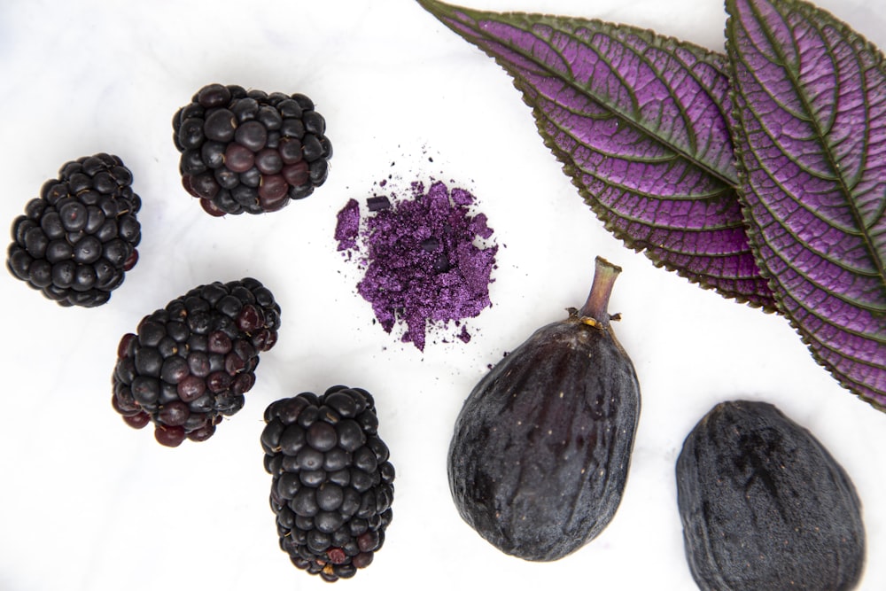 purple round fruit on white surface