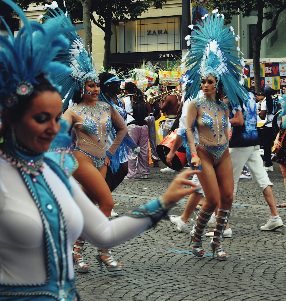 woman in blue and white feather costume standing on gray concrete floor during daytime