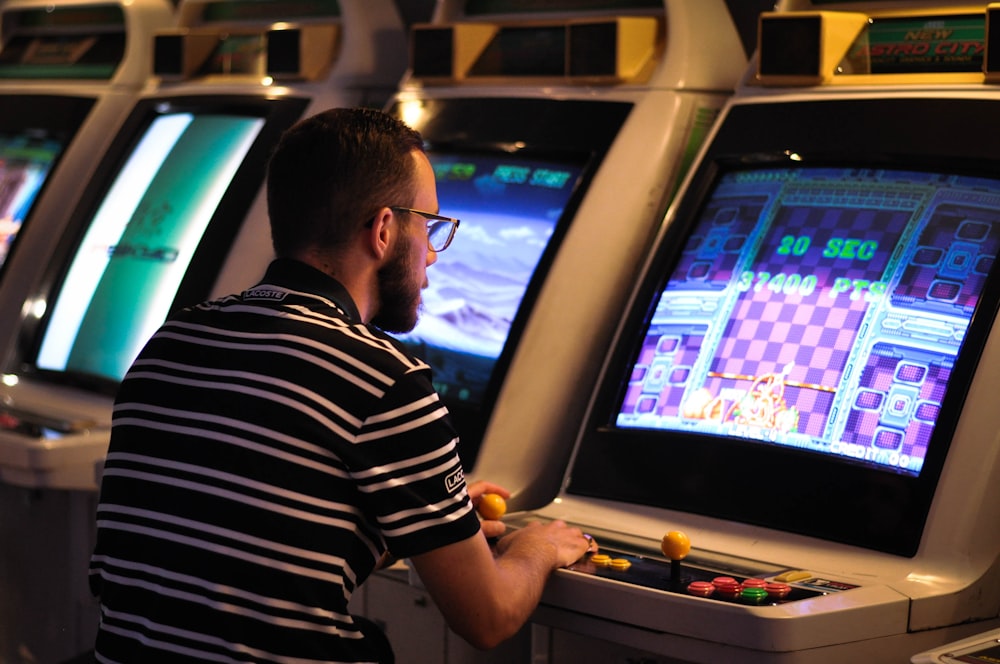 man in black and white striped shirt playing arcade game