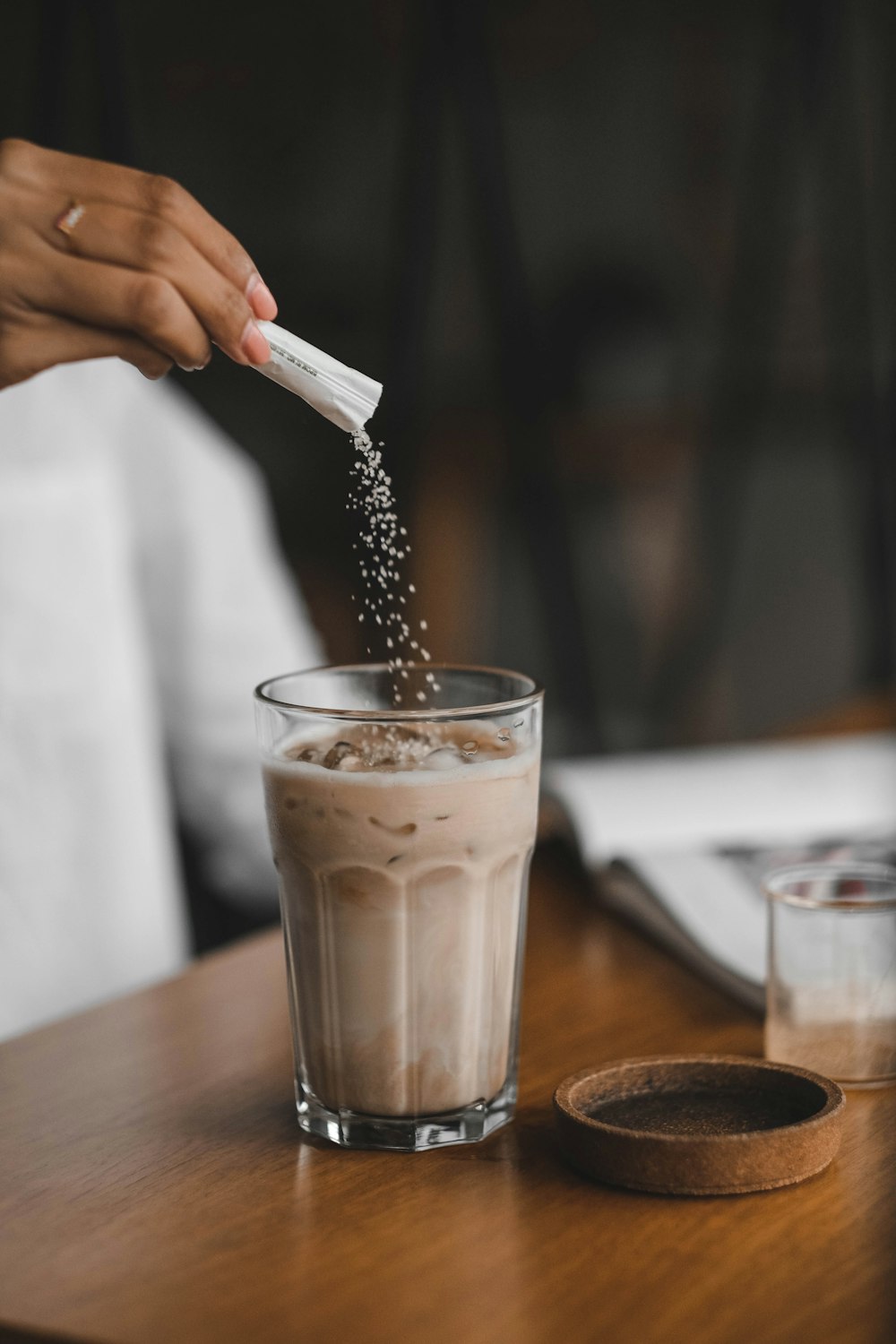 person holding clear drinking glass with brown liquid