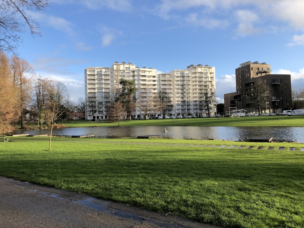 Campo de hierba verde cerca de los edificios de la ciudad bajo el cielo azul durante el día