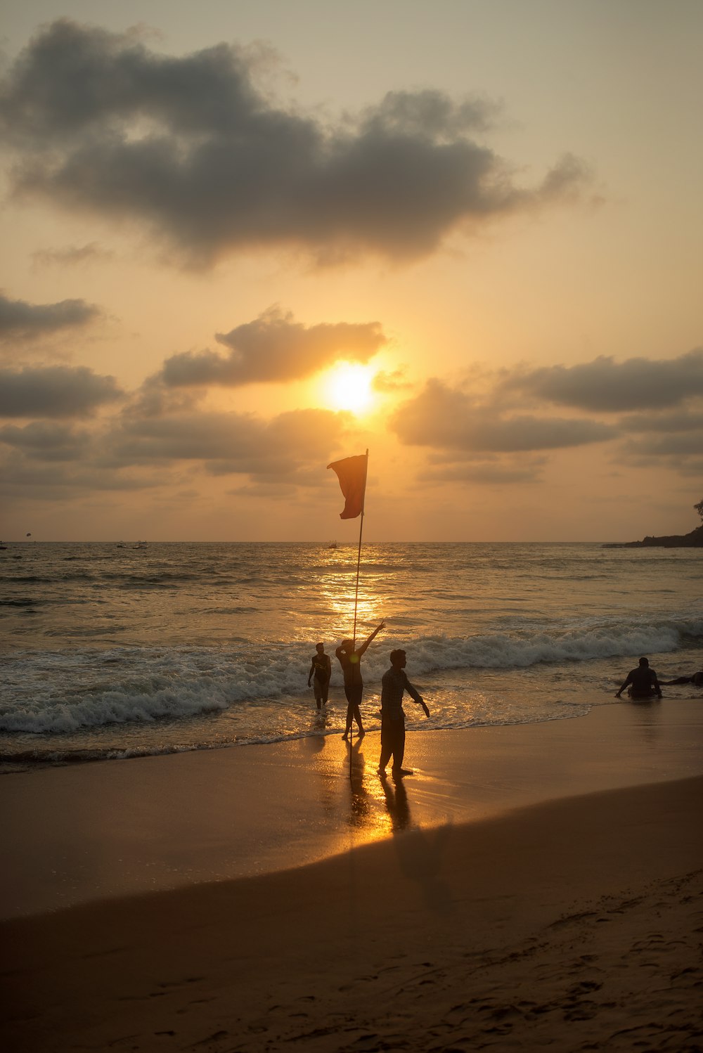 silhouette of 2 person holding umbrella walking on beach during sunset