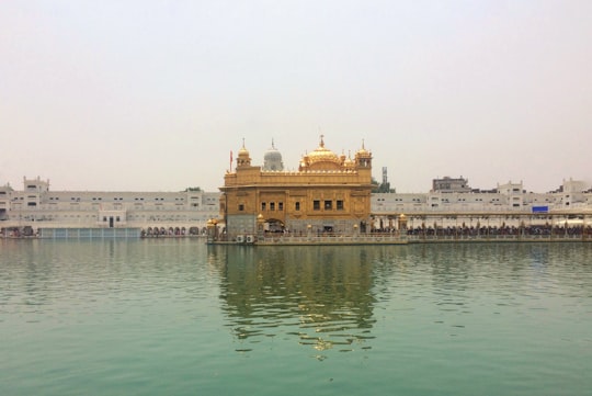 brown concrete building near body of water during daytime in Harmandir Sahib India
