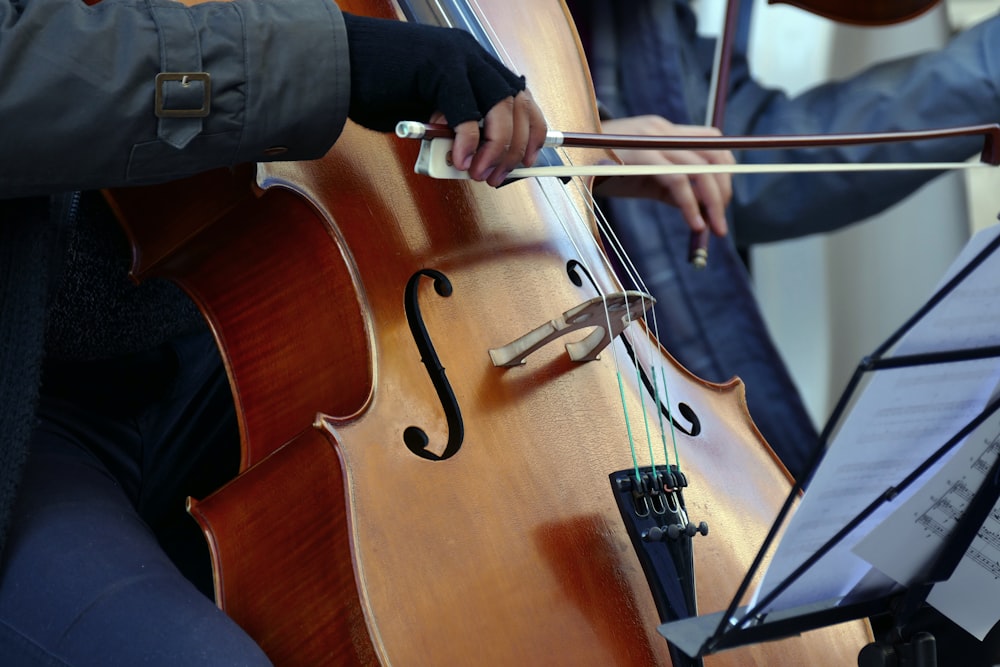 Persona con camisa negra de manga larga tocando el violín marrón