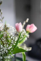 Close-up of a delicate arrangement combining white lilies with soft pink tulips on a light pastel background.